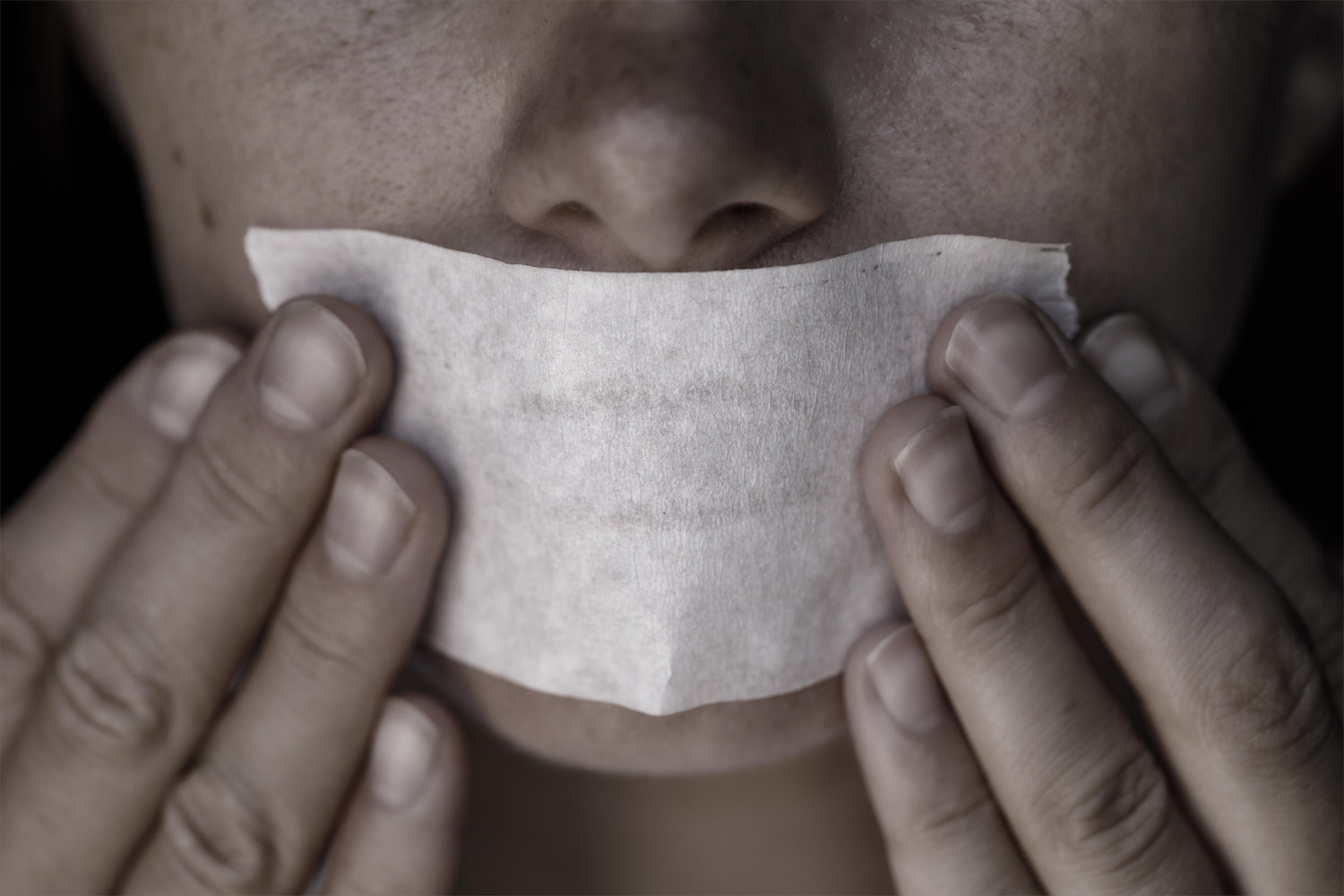 Nahaufnahme: Hände drücken ein Klebeband auf einen Mund