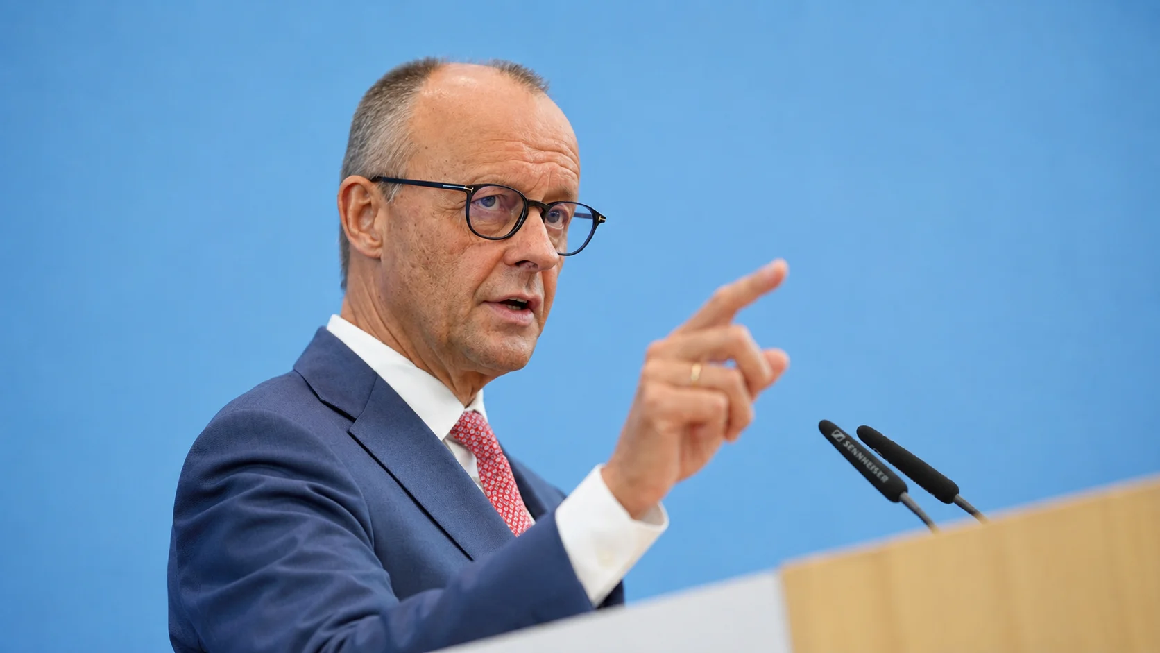 KI-generierte Illustration: Friedrich Merz spricht mit erhobenem Zeigefinger bei einer Pressekonferenz